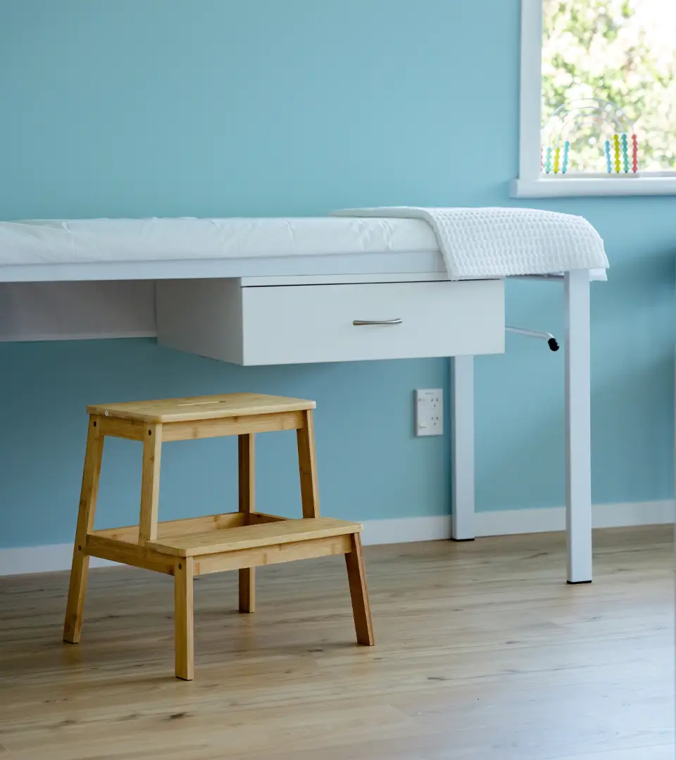 Medical table with wooden stepping stool in front